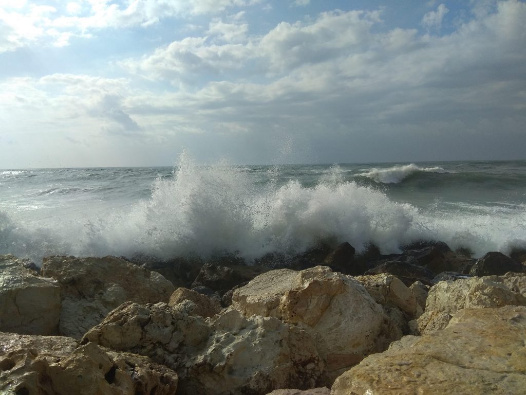 גלים מתנפצים אל הסלעים בים