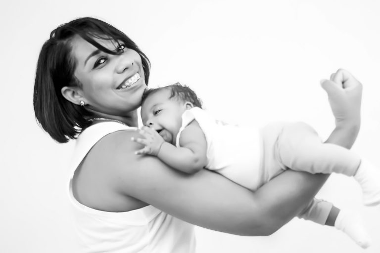 אישה מחזיקה תינוק על הזרוע ומחייכת